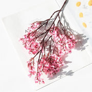 Pink artificial flower branch on a white background