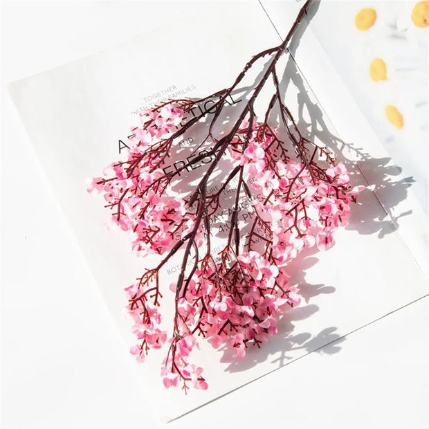 Pink artificial flower branch on a white background