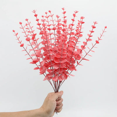 Hand holding a bouquet of red artificial flowers against a white background