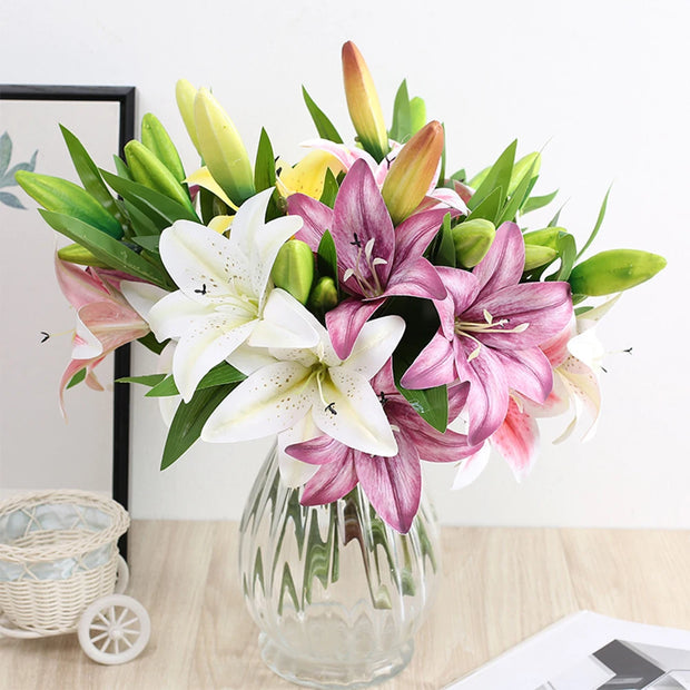 Bouquet of flowers in a clear vase on a wooden surface with a white wall background