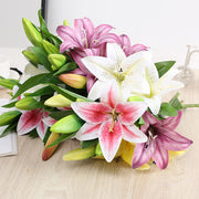 Bouquet of pink, white, and green lilies on a light wooden surface.
