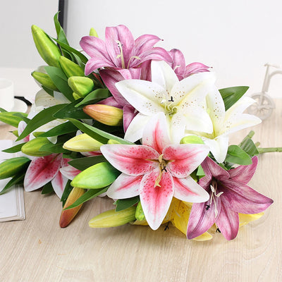 Bouquet of pink, white, and green lilies on a light wooden surface.