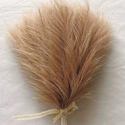 Feather duster with a beige ribbon on a light gray background