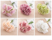 Set of six carnation flowers in different colors on a textured surface with a magazine background.