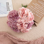 Pink and purple flowers on a light surface with a magazine and paper in the background