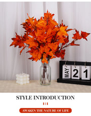 Orange artificial leaves in a glass vase on a table with a calendar and candle.