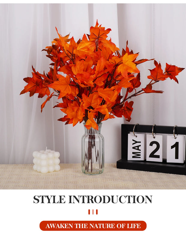 Orange artificial leaves in a glass vase on a table with a calendar and candle.