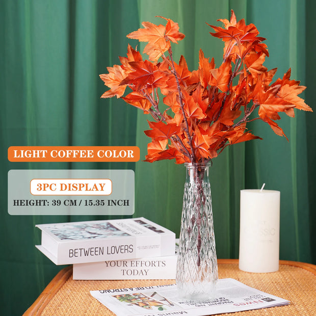 Vase with orange leaves on a table with books and a candle, against a green curtain background.