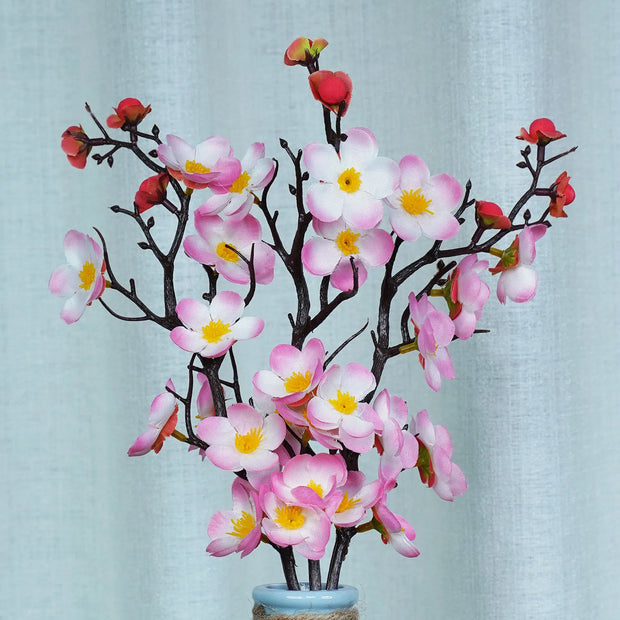 Artificial flower branch with pink flowers and yellow centers on a light blue background