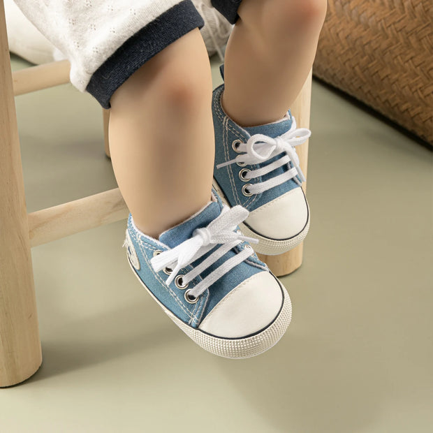 Child's feet wearing blue denim shoes with white soles on a neutral background