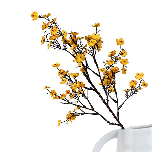 Yellow artificial flower branch with a white cup on a white background