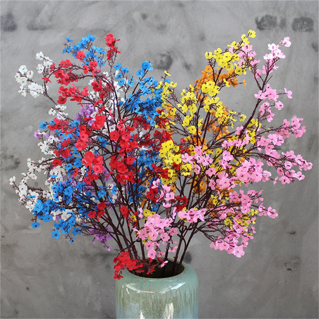 Colorful artificial flowers in a green vase against a gray background