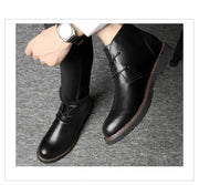 Black leather shoes worn by a person on a gray background