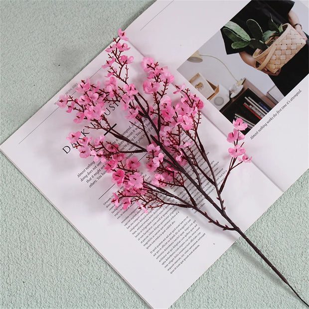 Pink artificial flower branch on an open magazine