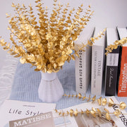 Gold leaf branches on a surface with books and a magazine.