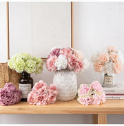 Decorative flowers in vases on a wooden surface with a neutral background