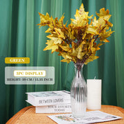 Decorative yellow leaf arrangement in a clear vase on a table with green curtain background