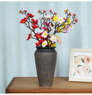 Decorative vase with colorful flowers on a wooden surface with a light blue wall background