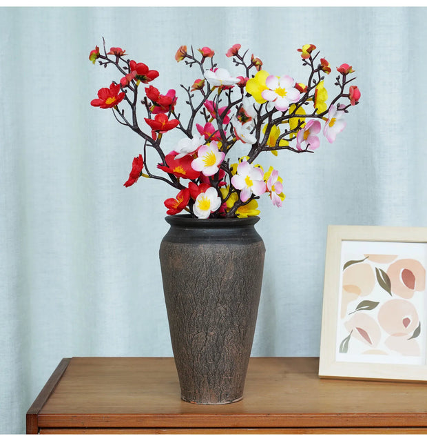 Decorative vase with colorful flowers on a wooden surface with a light blue wall background