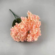 Pink artificial hydrangea flower arrangement on a gray background