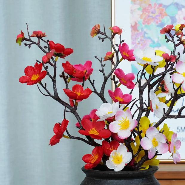Decorative floral arrangement with red, pink, and white flowers in a pot.