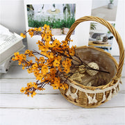 Wicker basket with decorative elements and yellow flowers on a light wooden surface.