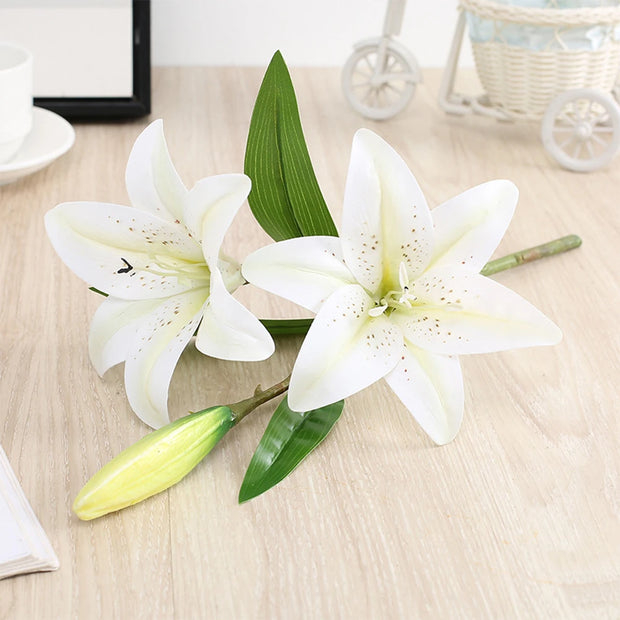 Two white lilies on a wooden surface with a blurred background