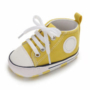 Yellow baby shoe with white laces on a white background