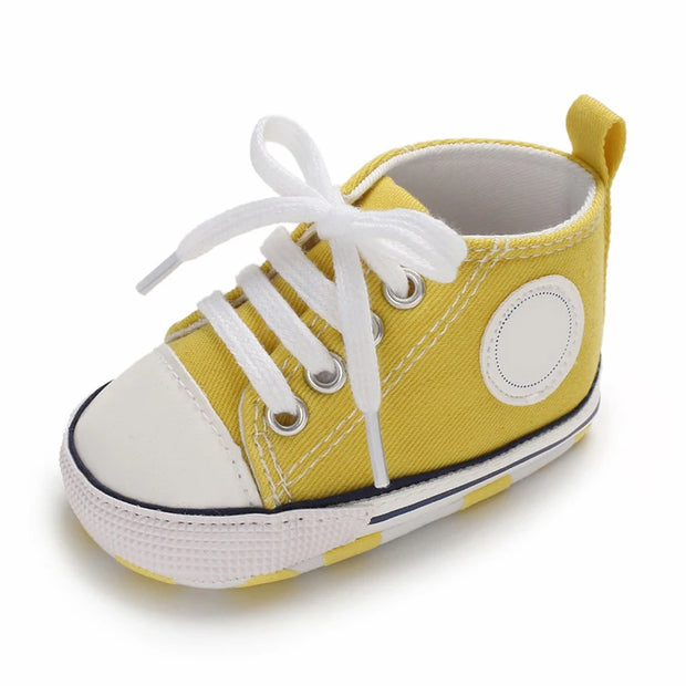 Yellow baby shoe with white laces on a white background