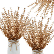 Gold leafed branches in white vases on a white background