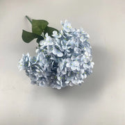 Artificial blue hydrangea flower arrangement on a light background