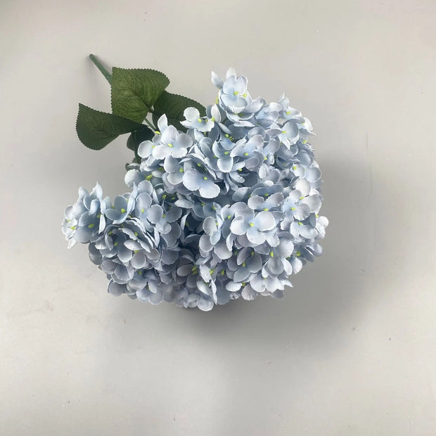 Artificial blue hydrangea flower arrangement on a light background