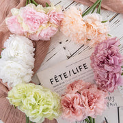 Colorful flowers arranged around a magazine titled 'Fète/Life' on a wooden surface.
