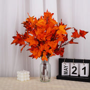Bouquet of orange leaves in a clear vase with a calendar displaying 'May 21' on a white curtain background.
