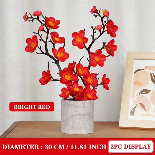 Red floral branches in a vase on a wooden surface with a neutral background