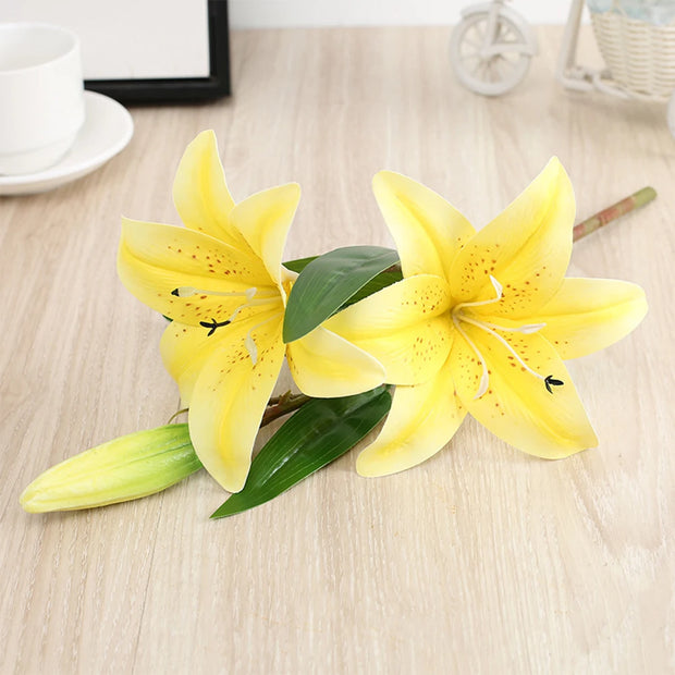 Two yellow lilies on a wooden surface with a blurred background