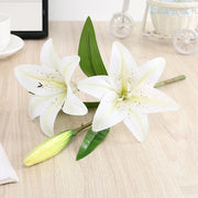Two white lilies on a wooden surface with a blurred background