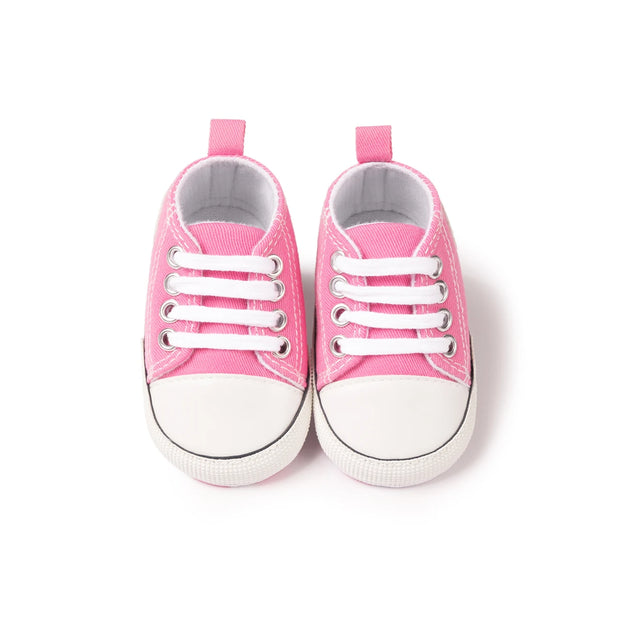 Pair of pink baby sneakers on a white background