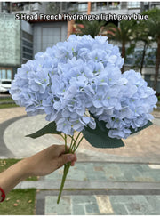 Bouquet of light gray blue French hydrangea held by a person outdoors.