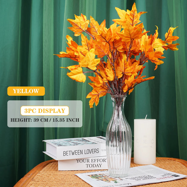 Yellow artificial leaves in a clear vase on a table with green curtain background
