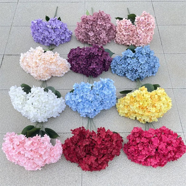 Assorted colored hydrangeas arranged in a grid on a tiled floor.