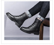 Black leather boots worn with jeans on a light gray background