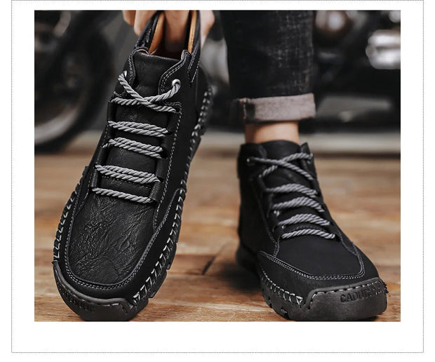 Black leather boots with gray laces on a wooden floor.