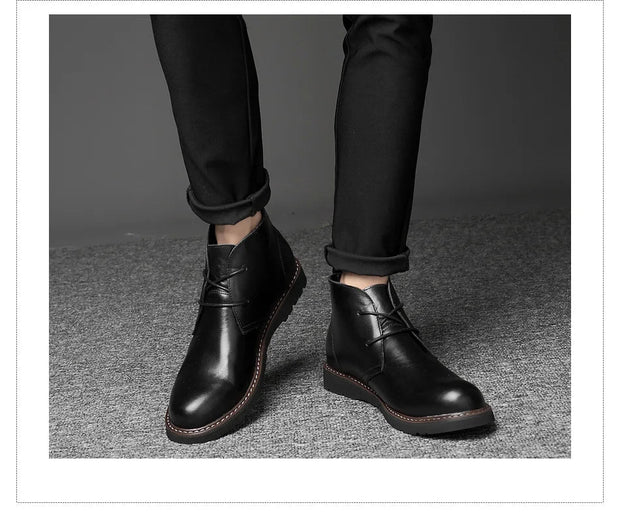 Black leather boots worn with black pants on a gray background