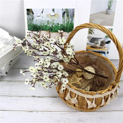 Wicker basket with decorative branches on a light wooden surface