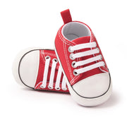 Red baby sneakers with white laces on a white background
