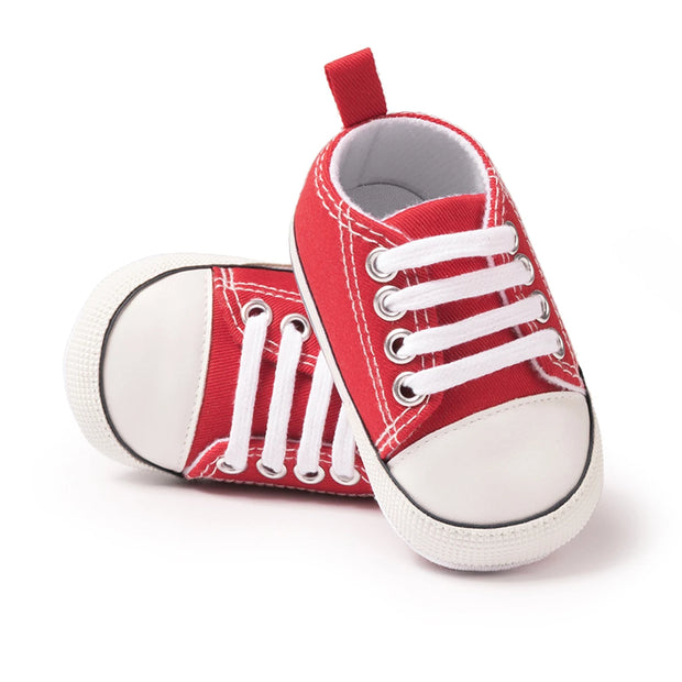 Red baby sneakers with white laces on a white background