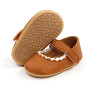 Pair of brown children's shoes with a strap on a white background