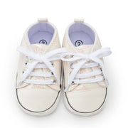 Pair of white baby sneakers with colorful patterns on a white background