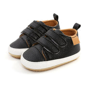 Pair of black children's shoes with brown accents on a white background